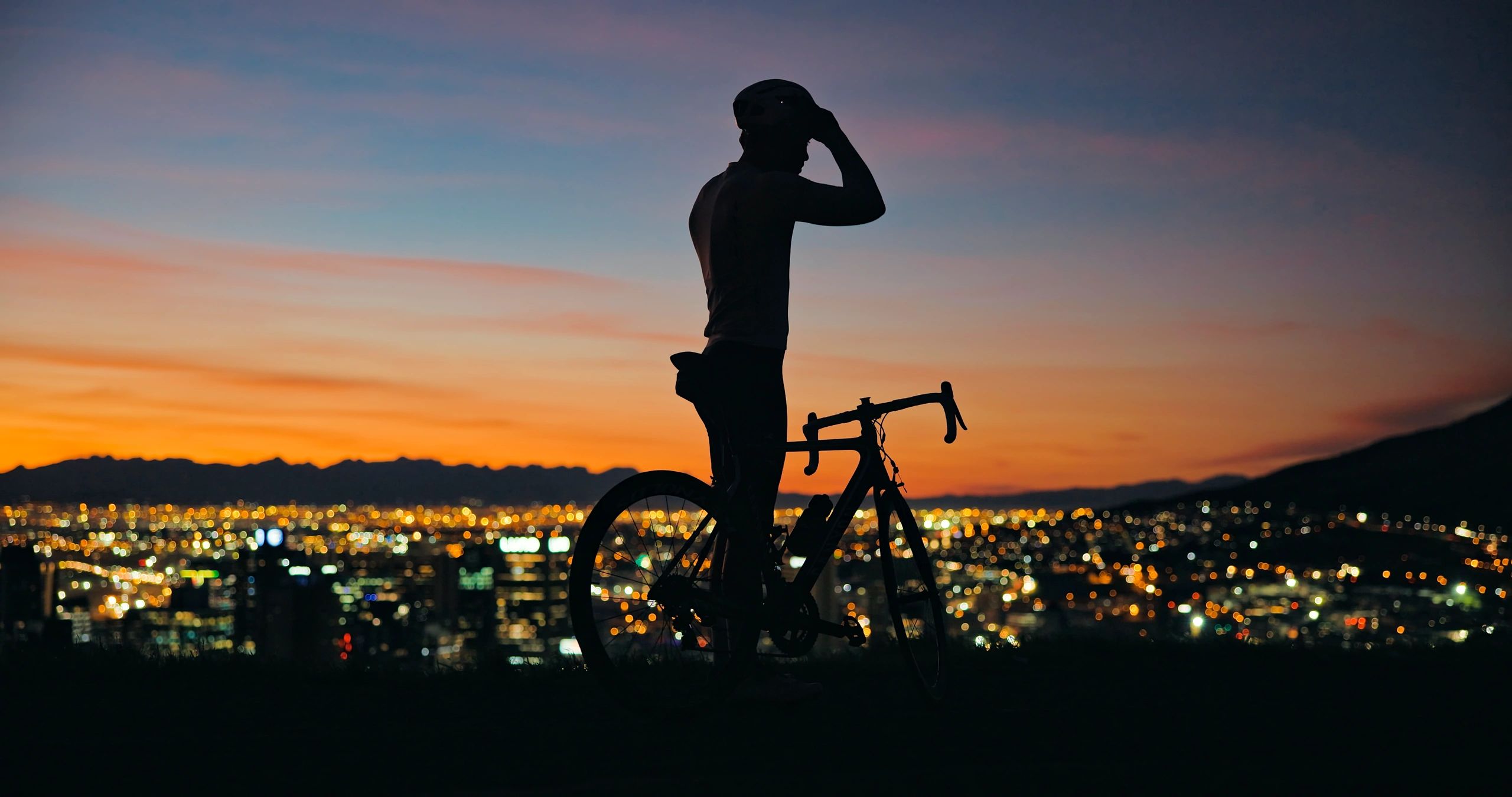 Road cyclist putting on a helmet at sunset